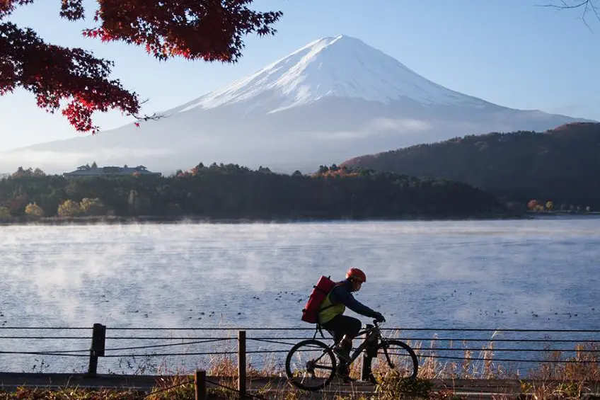 Cyclist near Lake Kawaguchiko with Mt. Fuji, showing rural Japan travel and internet access.