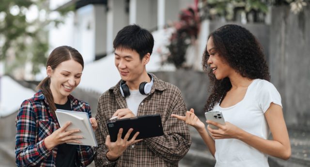 Students on campus having a discussion while using their devices