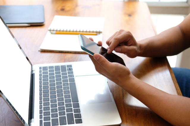 A person using their smartphone and laptop to get started with a Rakuten Mobile phone plan in Japan.