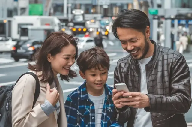 A family uses a smartphone to navigate around Tokyo.