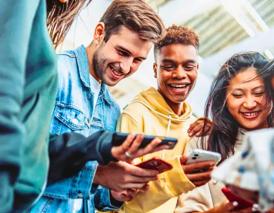 A group of friends huddled together, all on their phones, which are connected using a Pocket WiFi device while they travel throughout Japan.