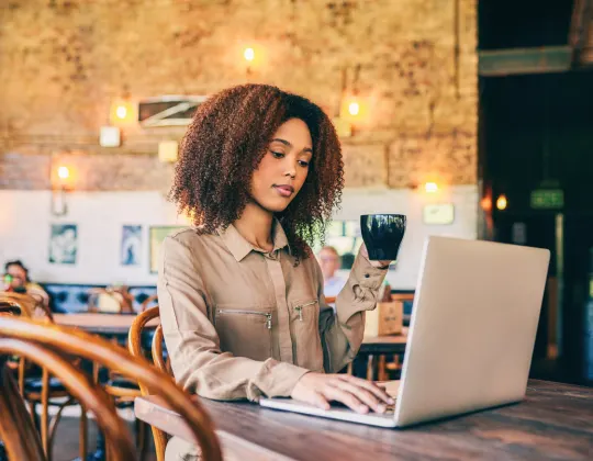 A woman in a public cafe doing work on her laptop using the cafe's free public WiFi.