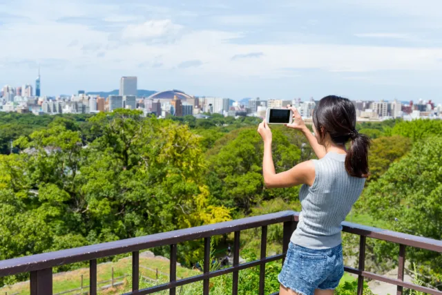 A woman taking a picture of the view of Fukuoka City.