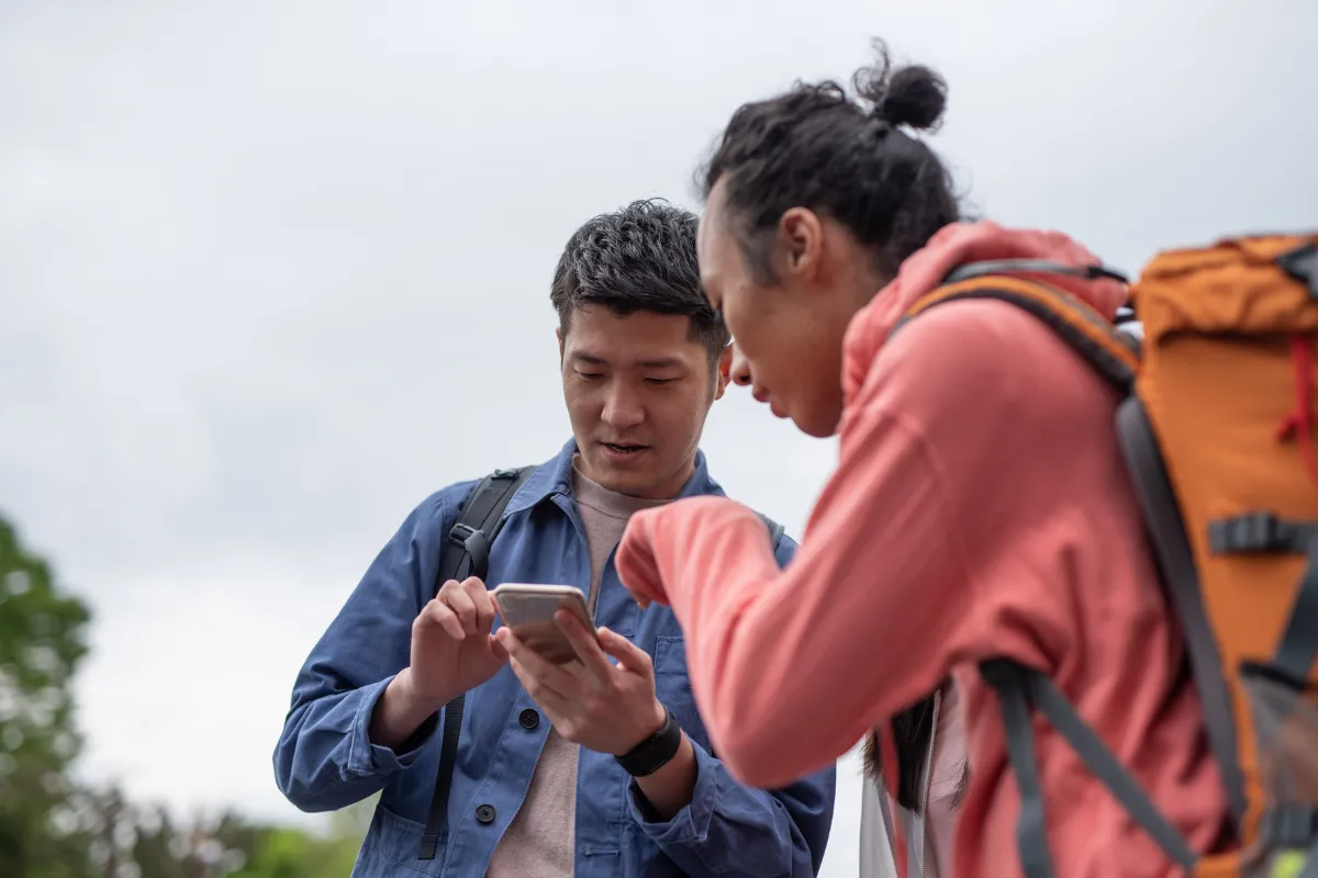 Two tourists using a smartphone in Japan, supported by a local eSIM with live English customer support and compatibility insurance.