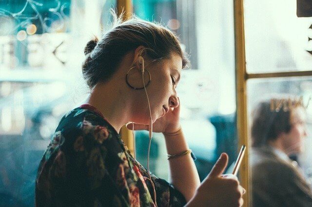 Women listening to music with headphones while relaxing in a coffee shop.