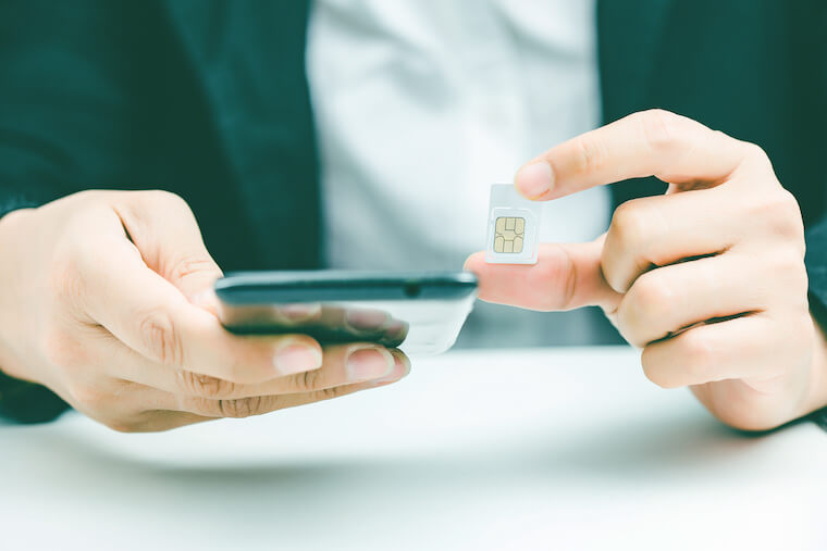 Close-up of a person inserting a SIM card into a mobile phone, demonstrating the setup process for travelers in Japan.